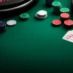 Close-up of poker chips and playing cards on a green casino table