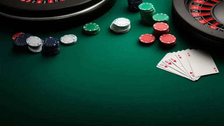 Close-up of poker chips and playing cards on a green casino table